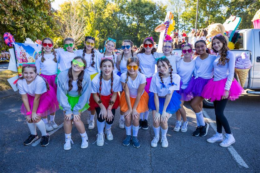 Middle school students wearing colored tutus smile